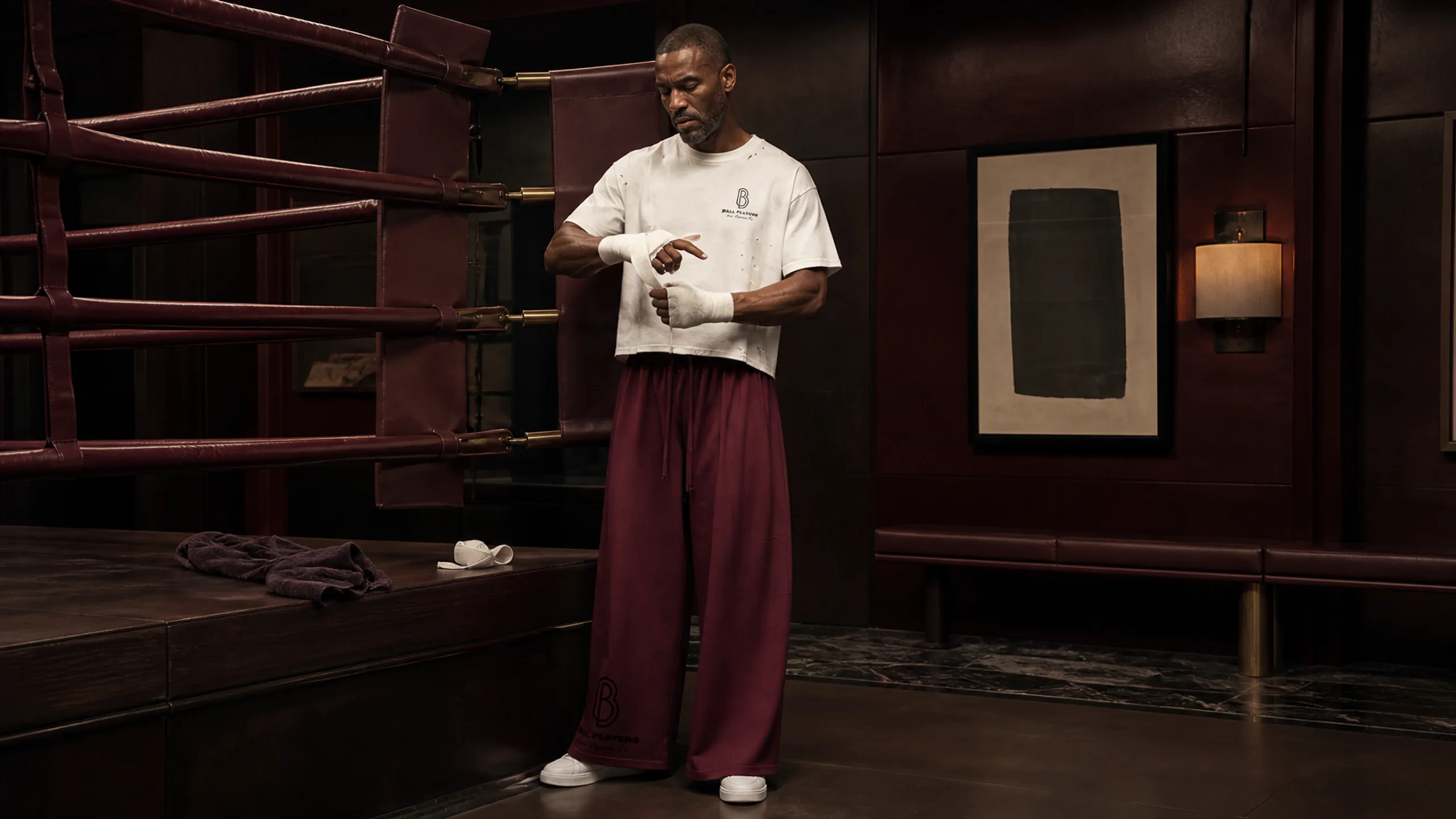 A man wearing Ball Players training apparel in an oxblood-leather private boxing salon.