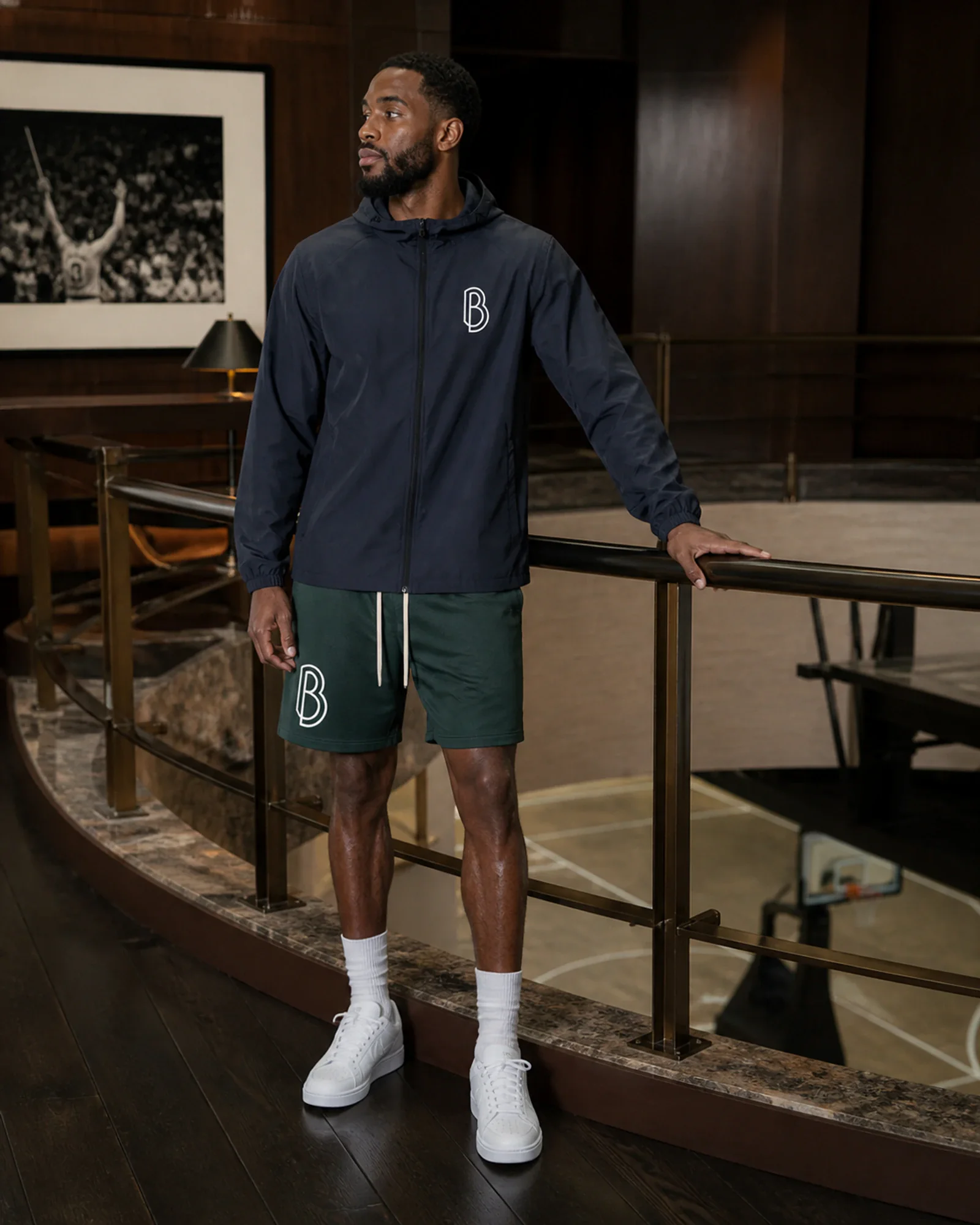 A man wearing a Ball Players hooded sports jacket in a mahogany basketball observation loge.